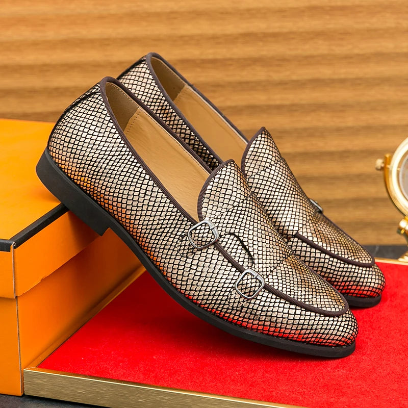 Pair of gold mesh loafers on a red surface with an orange box and wooden background